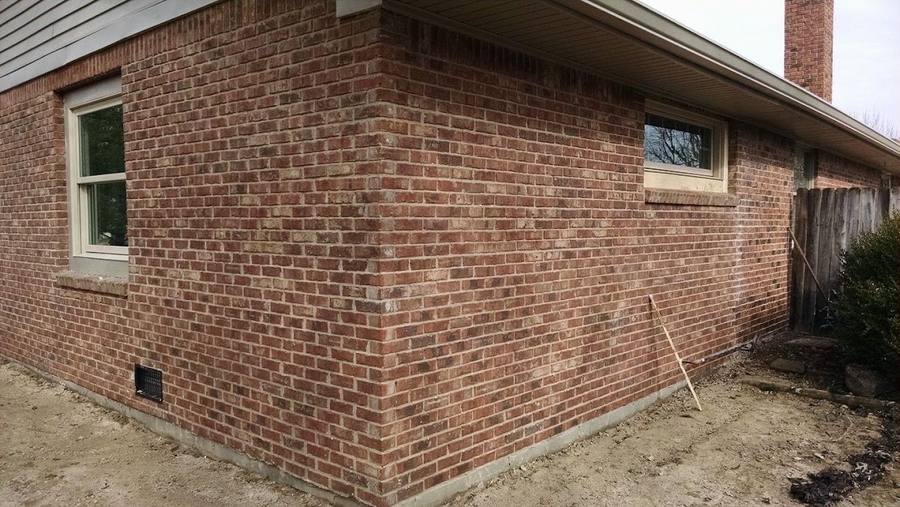 The outside corner of a single-storey brick house, the courses running level and unbroken up to the soffit, with a window on each face.